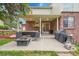Brick home exterior shows covered patio with seating, grill, and a fenced yard at 8646 Fawnwood Dr, Castle Pines, CO 80108