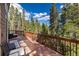 Spacious wooden deck with outdoor seating, surrounded by lush green trees and a clear blue sky at 302 Texas Dr, Idaho Springs, CO 80452
