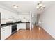 Bright kitchen features white cabinets, stainless steel appliances, and an open layout with access to the staircase at 8975 Field St # 39, Broomfield, CO 80021