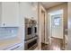 Built-in stainless oven and microwave in white kitchen near hallway at 8661 Hunters Hill Ln, Littleton, CO 80125