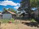 This backyard features a metal fence, a tool shed, weeds, and an open gate at 240 N 4Th Ave, Brighton, CO 80601