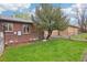 Charming backyard with brick home, green lawn and mature tree, enclosed by a chain link fence at 2459 S Corona St, Denver, CO 80210
