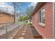 Exterior of a red brick house showing a fenced side yard and rock garden at 2459 S Corona St, Denver, CO 80210