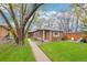 Charming brick home with a well-manicured lawn and mature trees, featuring a cozy outdoor seating area at 2459 S Corona St, Denver, CO 80210