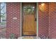 Close-up of a charming brick home's front door with a wreath, and a decorative floral mat at 2459 S Corona St, Denver, CO 80210