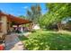 Lush backyard featuring a covered patio, grassy area, shed and mature trees at 8960 Judson St, Westminster, CO 80031