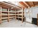 Unfinished basement storage area with exposed wood shelves and concrete floor at 7390 Rafter Rd, Franktown, CO 80116