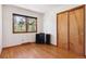 Bedroom with hardwood floors and large window, offering natural light and closet storage at 7390 Rafter Rd, Franktown, CO 80116
