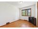 Simple bedroom featuring gleaming hardwood floors, white walls, and large window at 7390 Rafter Rd, Franktown, CO 80116