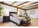 Large main bedroom with exposed beam ceiling, bench seating, and hardwood floors at 7390 Rafter Rd, Franktown, CO 80116