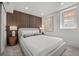 Well-lit basement bedroom with a large bed, cozy carpet, wood paneling, and a bright window at 2569 Forest St, Denver, CO 80207