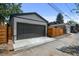 Exterior view of a detached garage with a large black door and newly poured concrete leading to the alley at 2569 Forest St, Denver, CO 80207