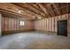 Spacious unfinished garage features concrete floor, exposed wooden beams and a black entry door at 2569 Forest St, Denver, CO 80207