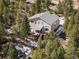 Aerial view of the home with a spacious deck surrounded by lush forest and rock outcroppings at 2120 Gross Dam Rd, Golden, CO 80403