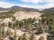 Aerial view of a peaceful home nestled among trees, with scenic mountain views beyond at 2120 Gross Dam Rd, Golden, CO 80403