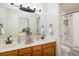 Bright bathroom featuring double sinks, wood cabinets, a large mirror, and a shower/tub at 2120 Gross Dam Rd, Golden, CO 80403