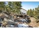 View of home with large deck surrounded by mature trees on a sloped lot at 2120 Gross Dam Rd, Golden, CO 80403