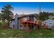 Exterior view of a charming home with a large deck, set against a backdrop of lush greenery and sunset sky at 812 Aspen Rd, Golden, CO 80401