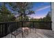 Balcony with chairs, rug, and table offers peaceful forest views under the evening sky at 13910 Blue Jay Ln, Larkspur, CO 80118