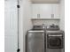 Well-equipped laundry room with modern washer and dryer, white cabinets, and ample storage space at 13910 Blue Jay Ln, Larkspur, CO 80118