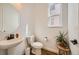Elegant powder room features a round mirror, modern toilet and pedestal sink at 8137 Ralston Creek Ave, Littleton, CO 80125