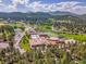 Overhead shot of a school surrounded by trees, mountains, and a football field, showcasing its idyllic location and facilities at 5336 High Rd, Evergreen, CO 80439