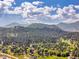 Aerial view of a town nestled among the trees with mountains in the distance on a beautiful day with a blue sky at 5336 High Rd, Evergreen, CO 80439