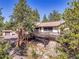 Charming home exterior with a wrap-around deck, mature trees, and natural rock landscaping on a sunny day at 5336 High Rd, Evergreen, CO 80439