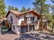 Two-story stucco home with tile roof, balconies, and two-car garage amid mature trees at 5336 High Rd, Evergreen, CO 80439