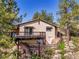Exterior view of house featuring a balcony and stone foundation surrounded by trees at 5336 High Rd, Evergreen, CO 80439