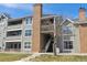 Multi-level condo building with brick chimney, wood siding, and stairs leading to the upper units at 12093 W Cross Dr # 304, Littleton, CO 80127