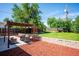 Landscaped backyard with green lawn, patio with pergola, and brick retaining wall at 1955 Ingalls St, Lakewood, CO 80214