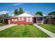 Charming red single-story home with a well-manicured front yard and white trim accents on a sunny day at 1955 Ingalls St, Lakewood, CO 80214