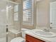 Bright bathroom featuring tiled shower, white vanity, a toilet and plantation shutters at 10761 Hillsboro Cir, Parker, CO 80134