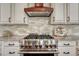 Gourmet kitchen with stainless steel stove and hood range with custom backsplash and marble countertops at 10761 Hillsboro Cir, Parker, CO 80134