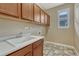 Functional laundry room features wood cabinets, a white sink, and a window for natural light at 10761 Hillsboro Cir, Parker, CO 80134