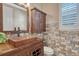 Charming powder room featuring wood cabinets, copper sink, brick accents, and natural light from the window at 10761 Hillsboro Cir, Parker, CO 80134