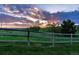 Scenic backyard view with a wooden fence, lush greenery, and a beautiful sunset backdrop at 7289 Stroh Rd, Parker, CO 80134