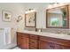 Bathroom featuring double sink vanity with wood cabinets, framed mirrors, and decorative mosaic tile backsplash at 7289 Stroh Rd, Parker, CO 80134