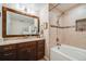 Well-lit bathroom with a large framed mirror, vanity, and a shower-tub combination with tiled accents at 9032 W Arizona Dr, Lakewood, CO 80232