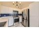 Well-lit kitchen featuring stainless steel appliances, white cabinetry and blue backsplash at 8358 Pebble Creek Way # 204, Highlands Ranch, CO 80126