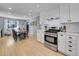 Bright, open kitchen with modern white cabinets, stainless steel appliances, and a view of the dining area at 6720 S Adams Way, Centennial, CO 80122