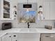 Charming kitchen sink with white cabinetry, open shelving, and a large window bringing in natural light at 6720 S Adams Way, Centennial, CO 80122