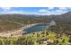 Scenic aerial view showcases a beautiful lake with a golf course surrounded by lush forests and mountains at 29827 Gigi Rd, Evergreen, CO 80439