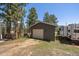 Detached gray garage with a white door, located near a trailer and surrounded by trees at 29827 Gigi Rd, Evergreen, CO 80439