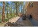Spacious stone patio with outdoor seating and mature pine trees at 29827 Gigi Rd, Evergreen, CO 80439
