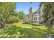 Picturesque backyard with mature trees, green grass, rock lined creek, and a gray house with many windows at 16257 E Belleview Pl, Centennial, CO 80015