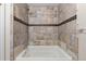 Tiled bathtub/shower combo boasts stylish earth-tone tiling, shower head, and sleek faucet at 63 S Holman Way, Golden, CO 80401