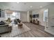 Open living room with gray sofa, wood floors, and TV stand at 10306 Uvalda Ct, Commerce City, CO 80022