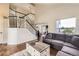 Open-concept living area featuring hardwood floors, staircase with black accents, and comfortable seating at 1663 E 96Th Pl, Thornton, CO 80229